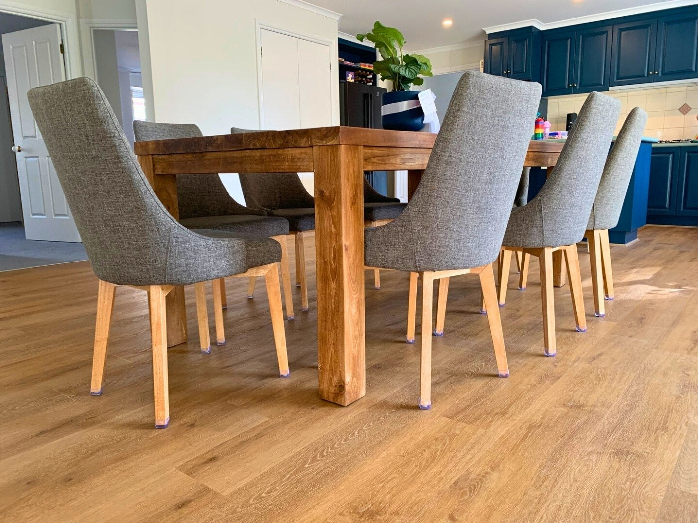 Dining table surrounded by chairs fitted with Chair Leg Caps on a timber floor